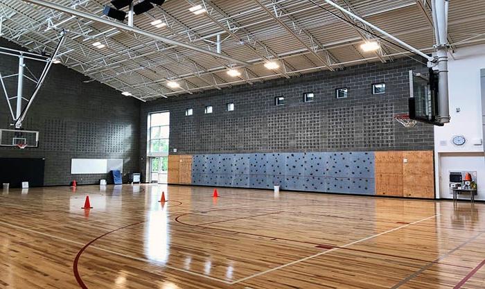 a gym with a climbing wall and basketball hoops
