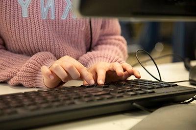 a child's hands are shown typing on a computer keyboard
