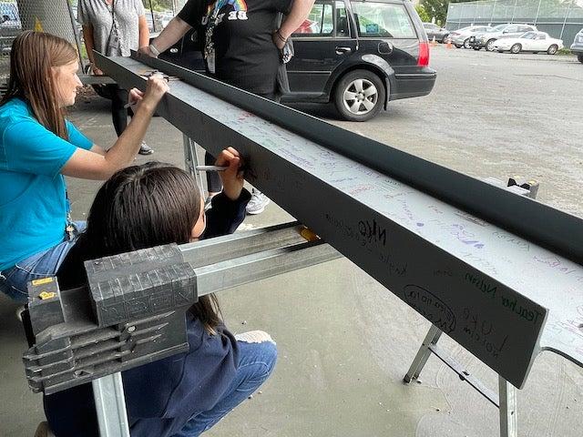 adult and child signing a steel beam outside