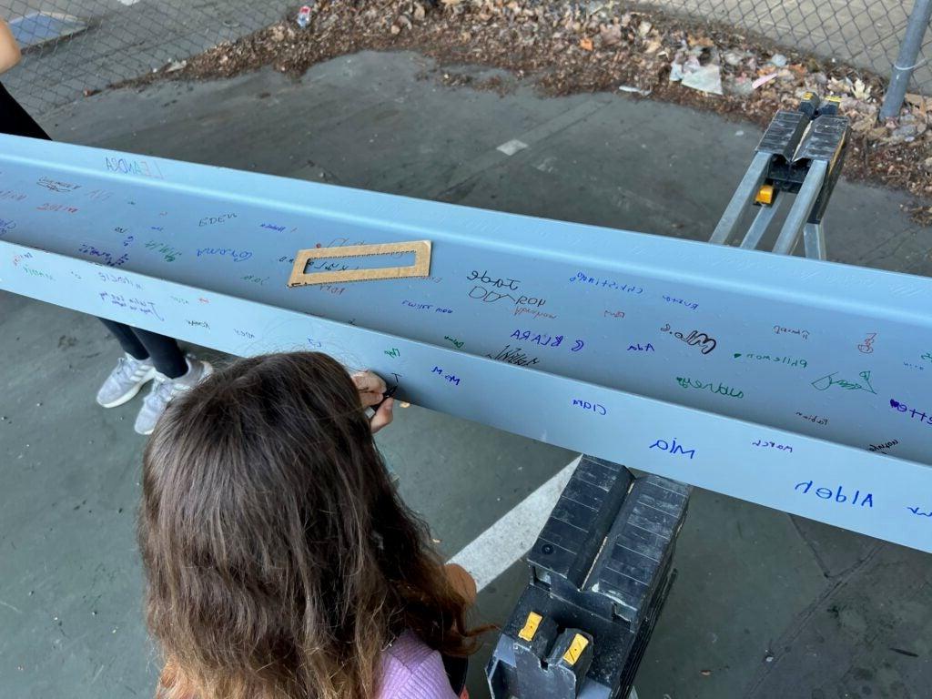 a child writes on a white steel beam