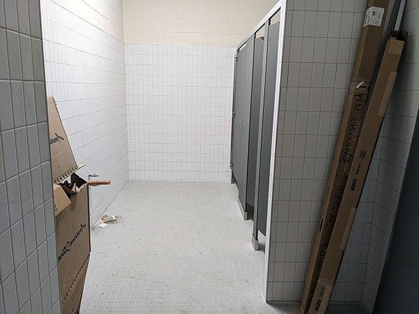白色瓷砖墙，左边有三个厕所隔间