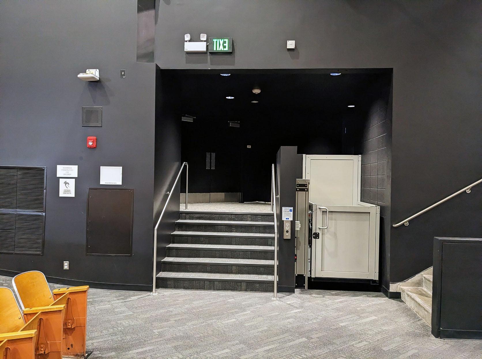 一个移动电梯被展示在六层楼梯的旁边，楼梯周围都是黑色的墙