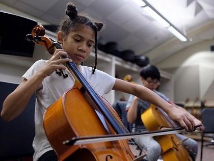 Two students play cellos in a music classroom.