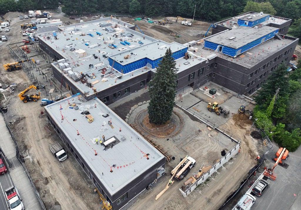 aerial of a large building with roofing work, and construction machines around it