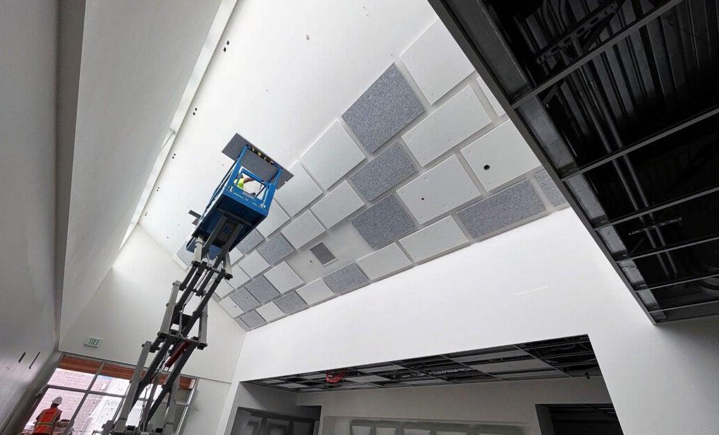 a person on a jacklift is installing ceiling tiles on an angled ceiling