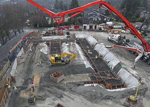 a construction site has a concrete pump truck installing concrete in a form