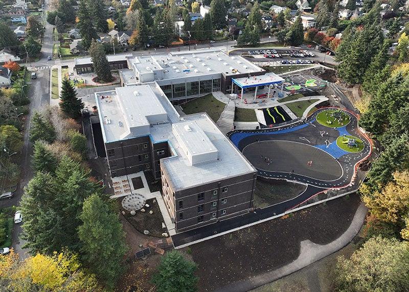 aerial view of a large L-shaped building with a playground
